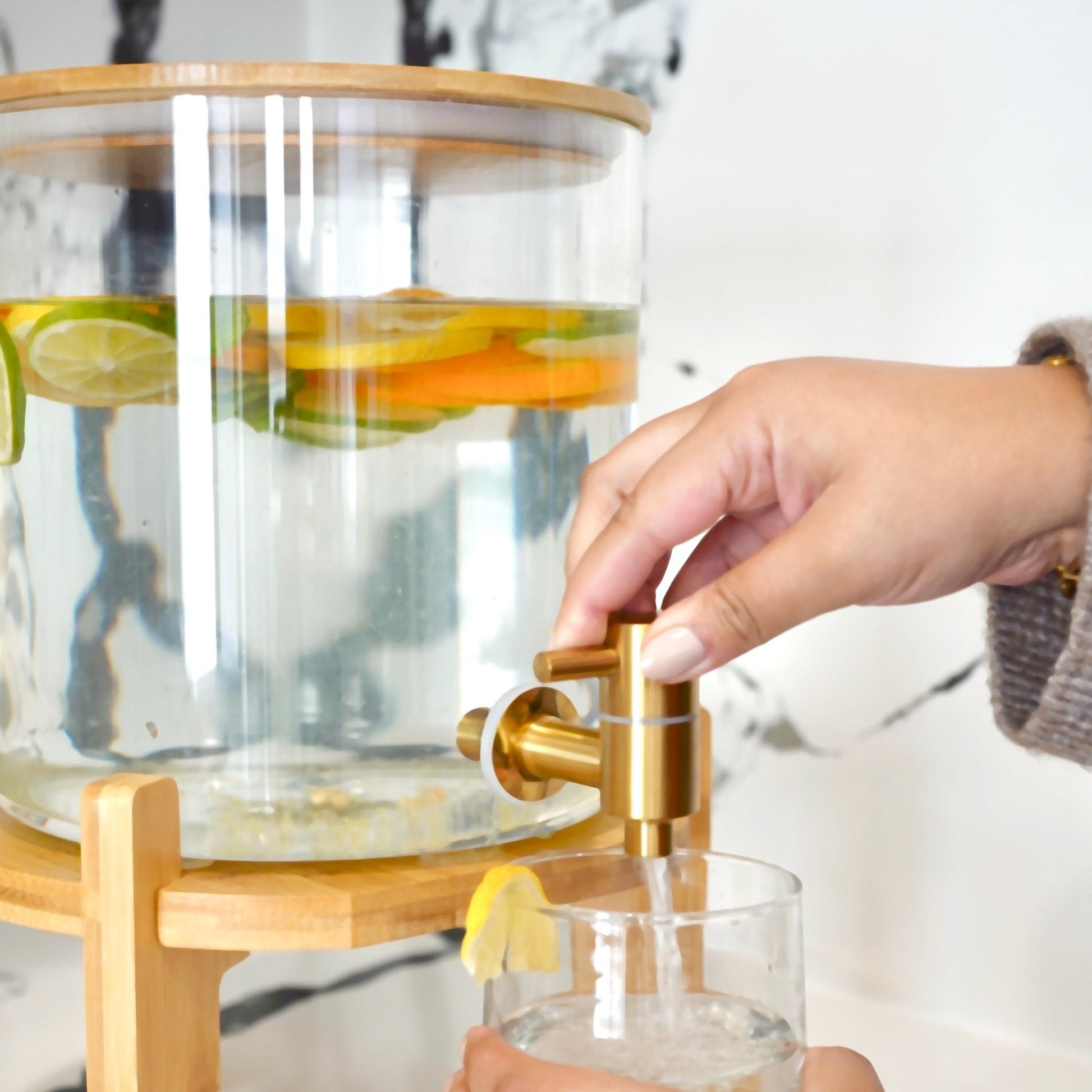 Glass carafe with lemon slices on a wooden stand, filled with water.