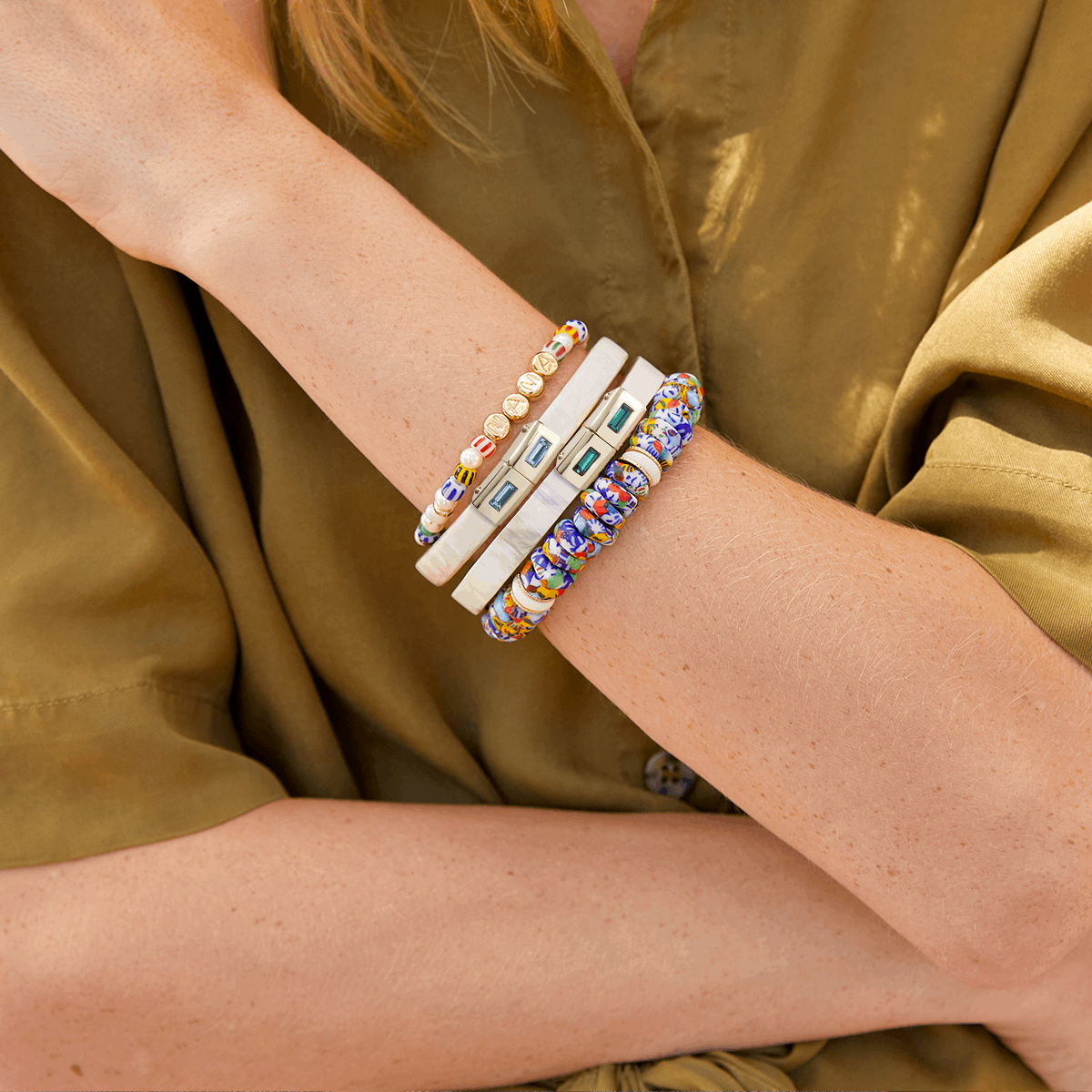 Close-up of a person's arm wearing colorful bracelets on a green background