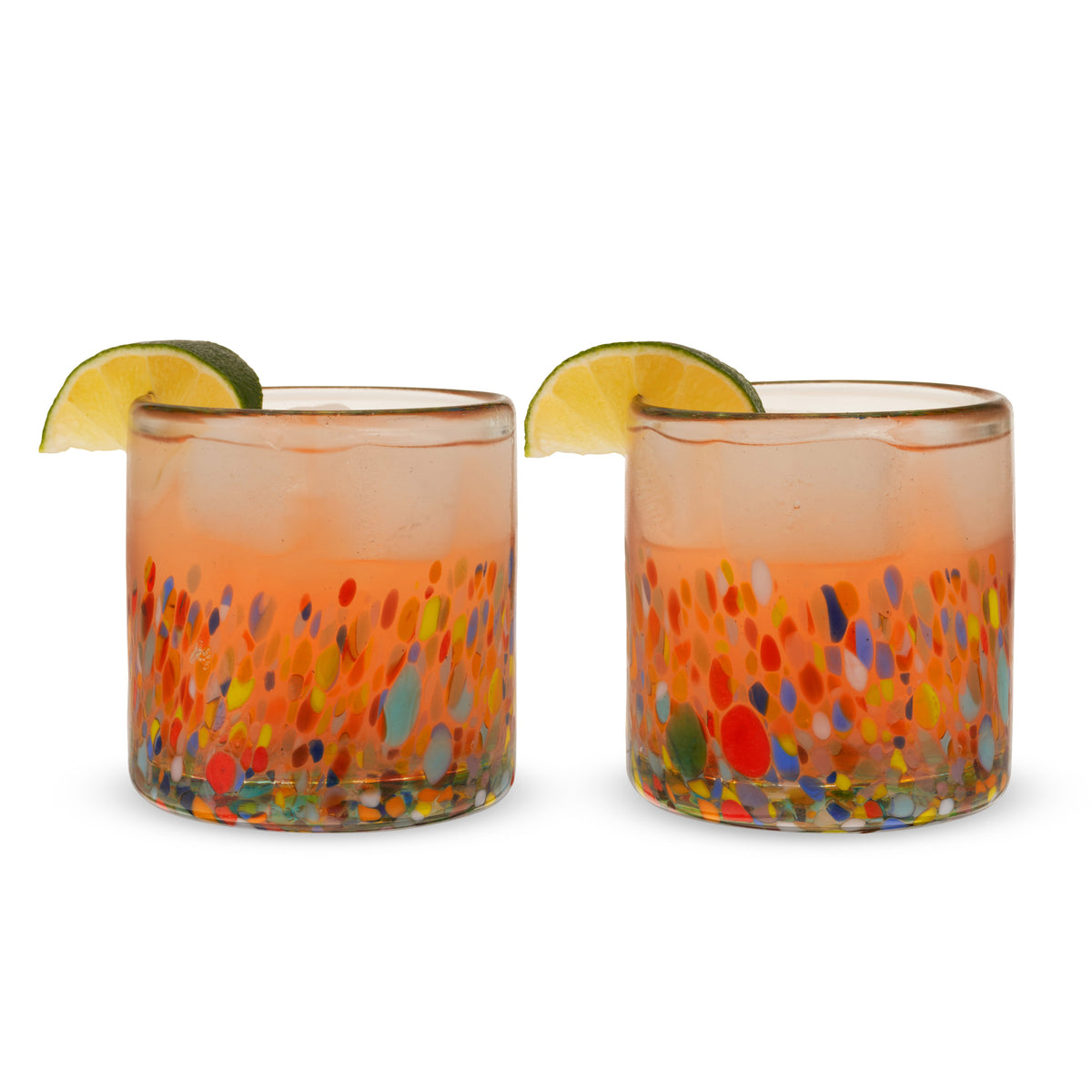 Two colorful speckled tumblers filled with pink drinks and garnished with lime wedges against a white background.