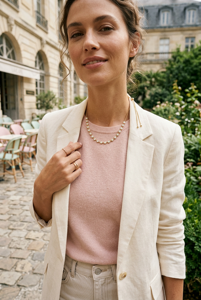 Model wearing the gold Lora bezel-set CZ necklace with a blush top and cream blazer outdoors.