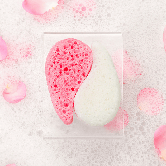 Pink and white half-moon soap with bubbles on a textured surface