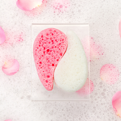 Pink and white half-moon soap with bubbles on a textured surface