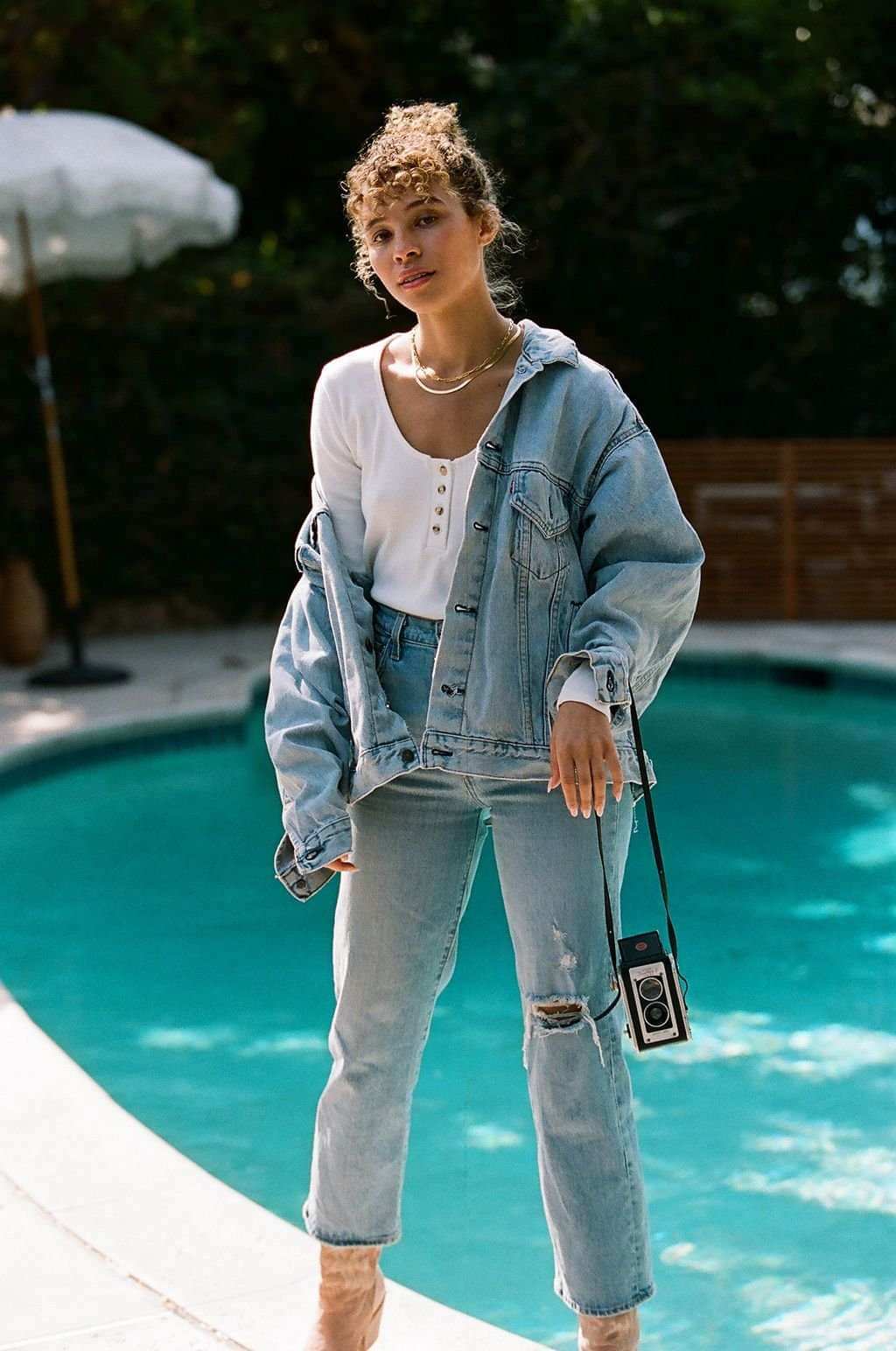 Person wearing a denim jacket and jeans by a pool