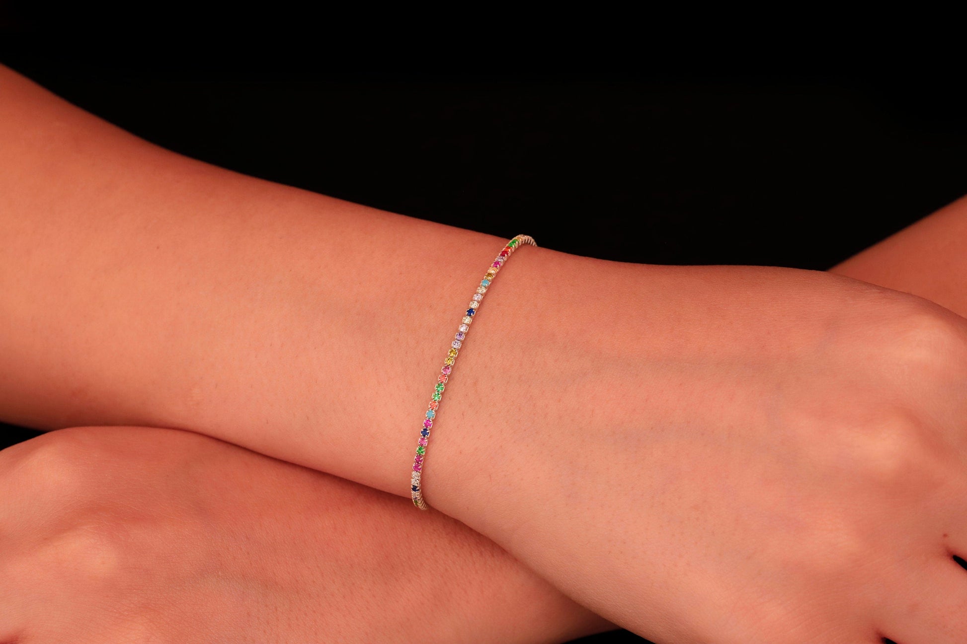 Colorful Dreams rainbow bracelet featuring multicolored stones set on a delicate gold band, worn on a wrist.