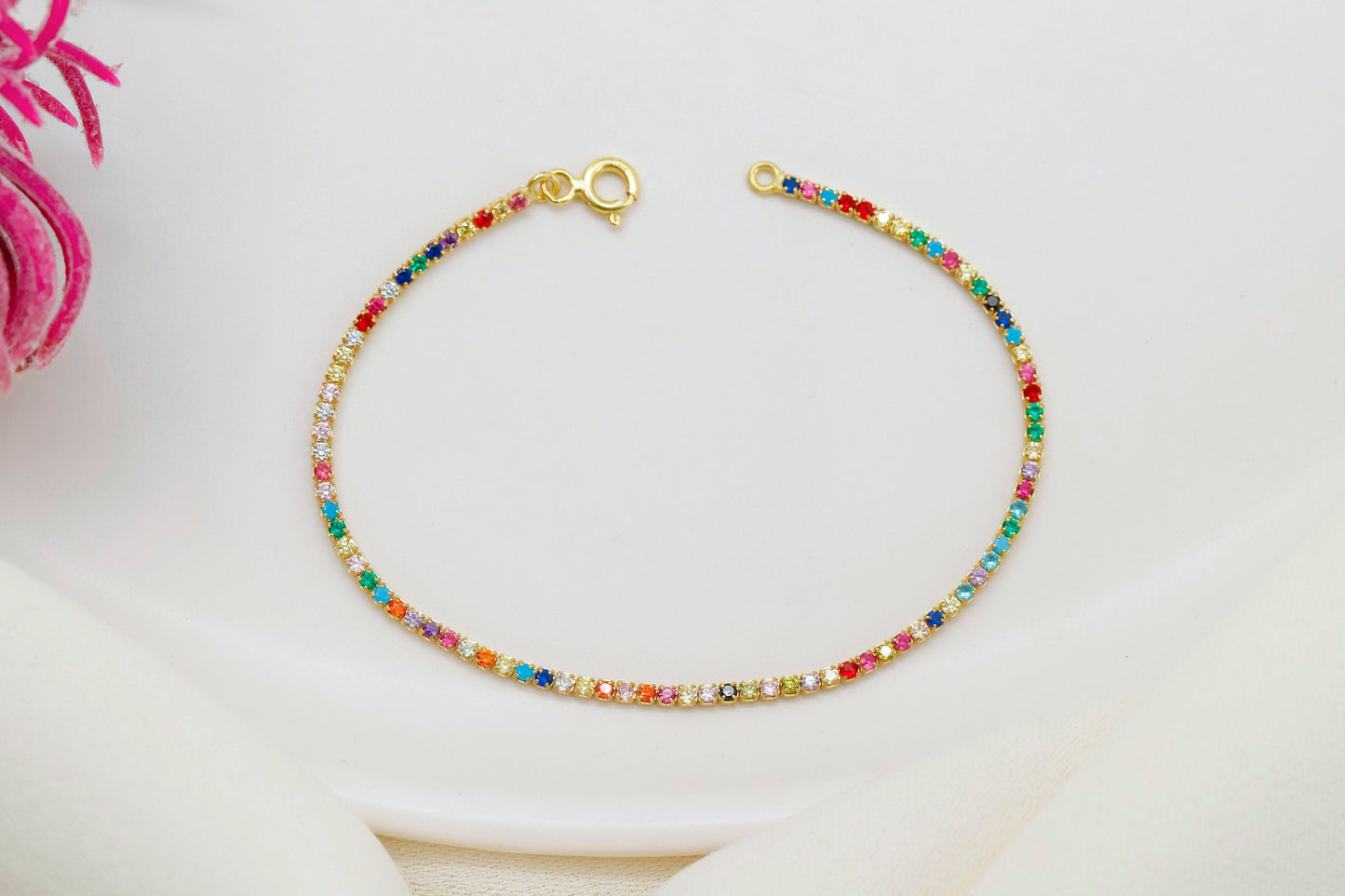 Colorful Dreams rainbow bracelet featuring multicolored gemstones set in a gold chain on a white background.