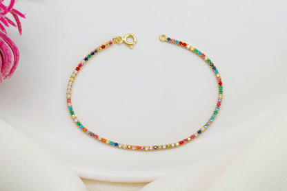 Colorful Dreams rainbow bracelet featuring multicolored gemstones set in a gold chain on a white background.