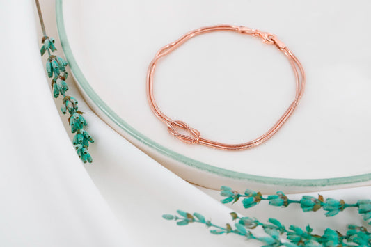 Rose gold bracelet on a white surface with green floral design