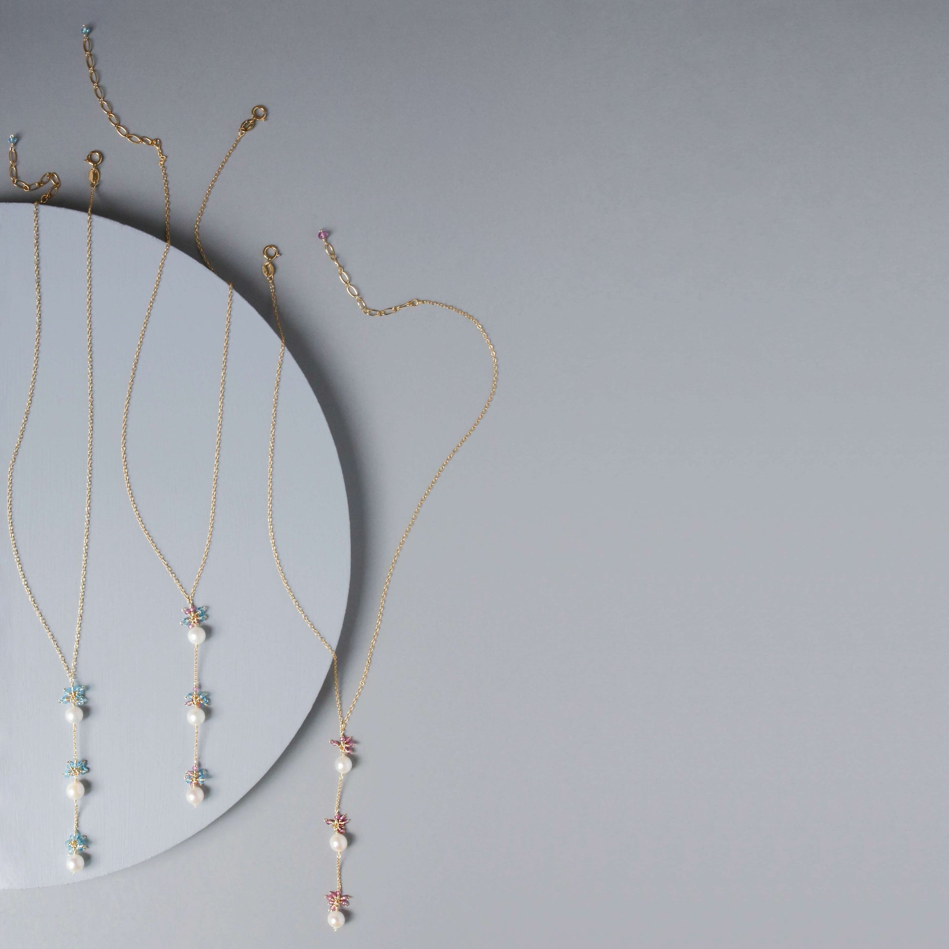 Gold necklaces with small pendants on a gray background