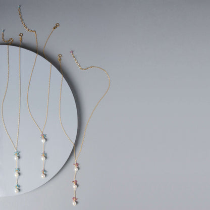 Gold necklaces with small pendants on a gray background