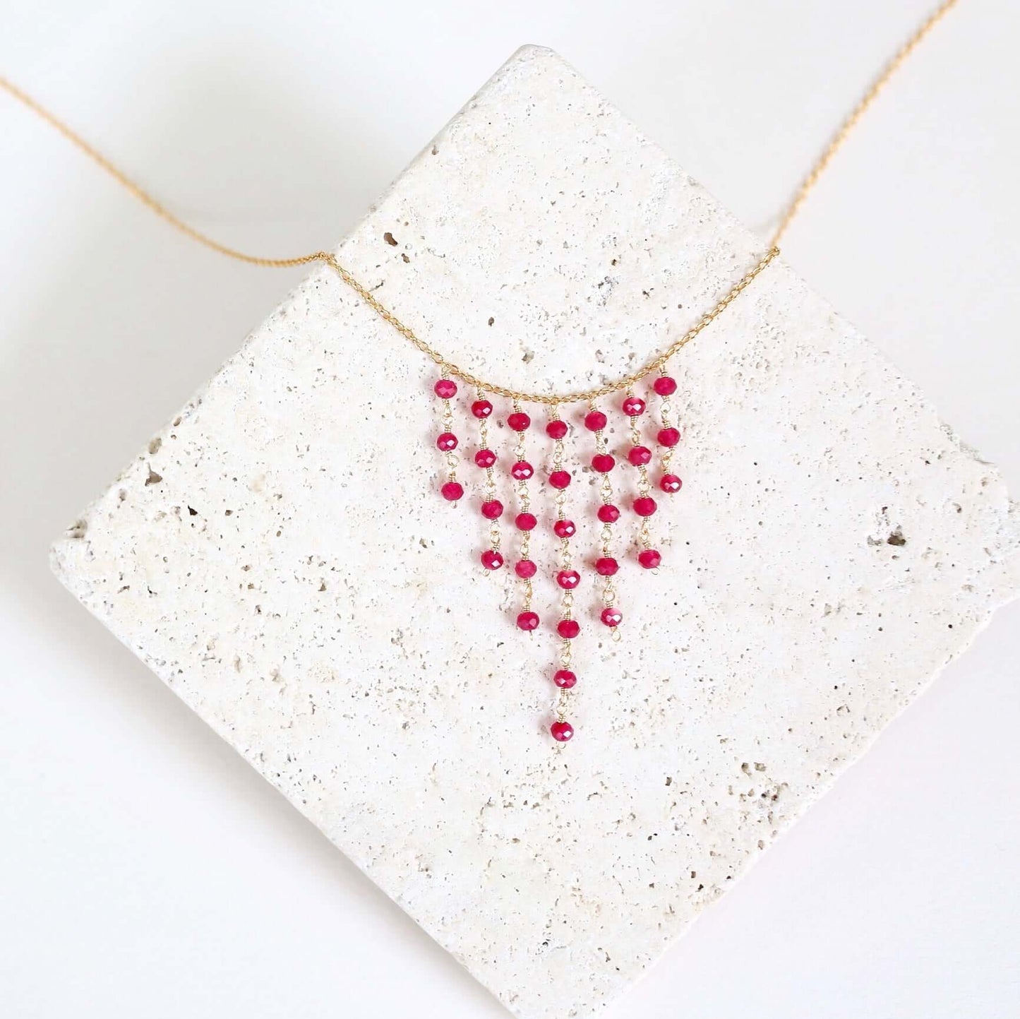 Necklace with red beads on a textured white surface