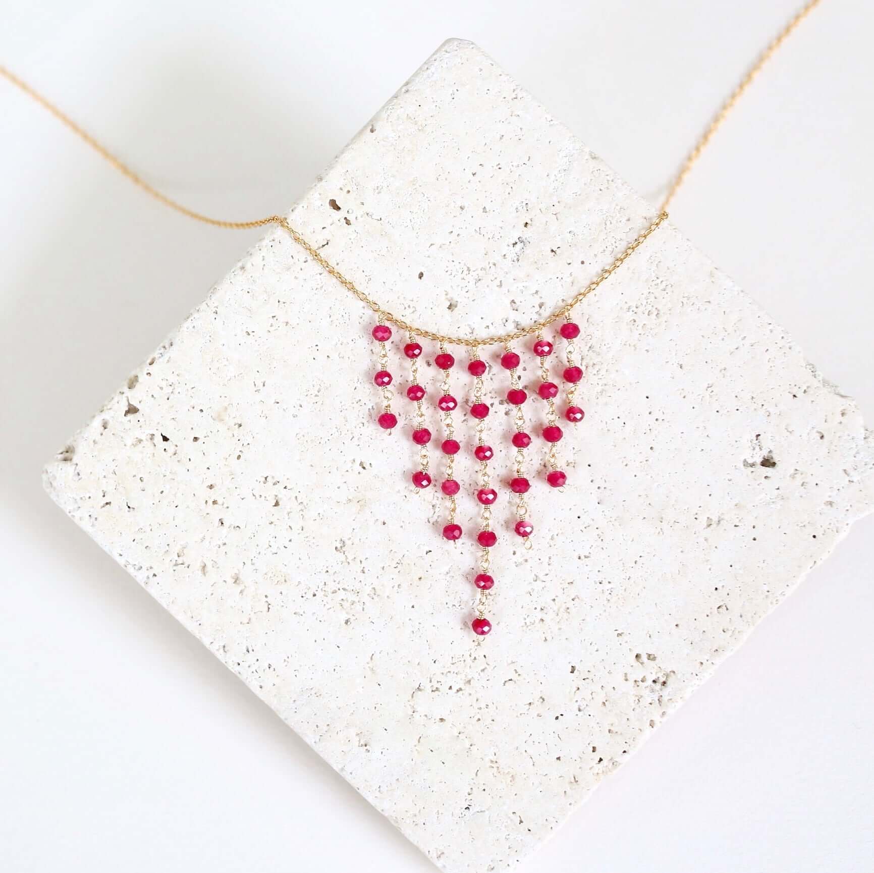 Necklace with red beads on a textured white surface