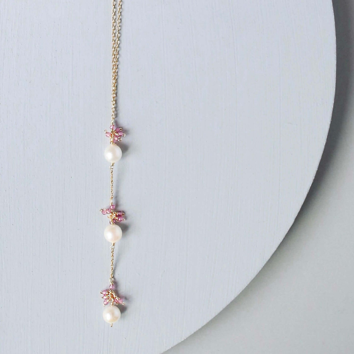 Necklace with pearls and floral elements on a light gray background