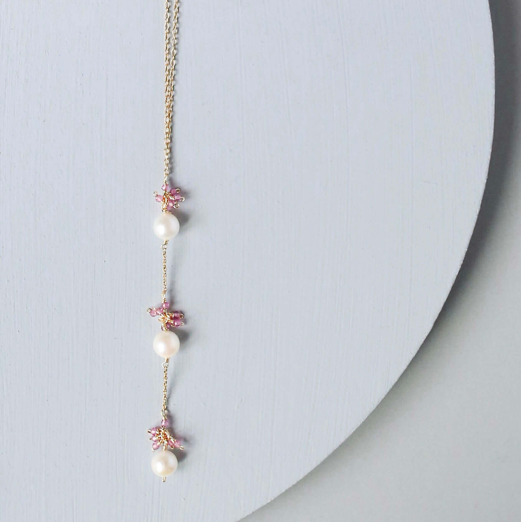 Necklace with pearls and floral elements on a light gray background