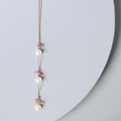 Necklace with pearls and floral elements on a light gray background