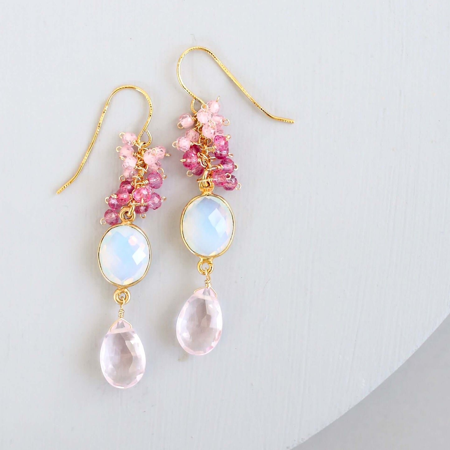 Pair of earrings with pink and gold accents on a light gray background