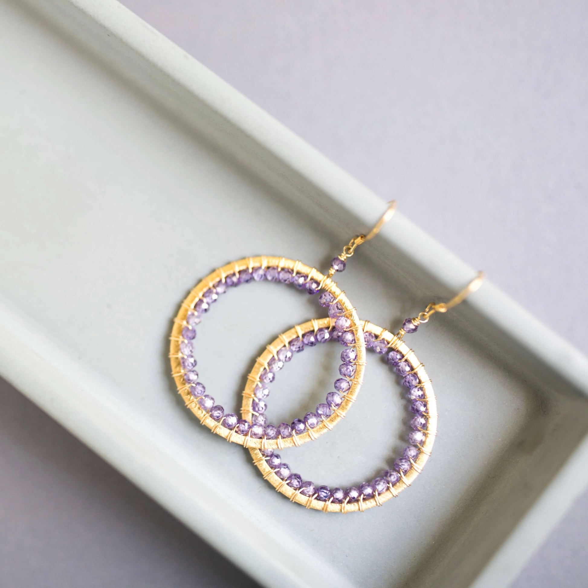 Purple beaded hoop earrings on a white tray