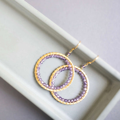 Purple beaded hoop earrings on a white tray
