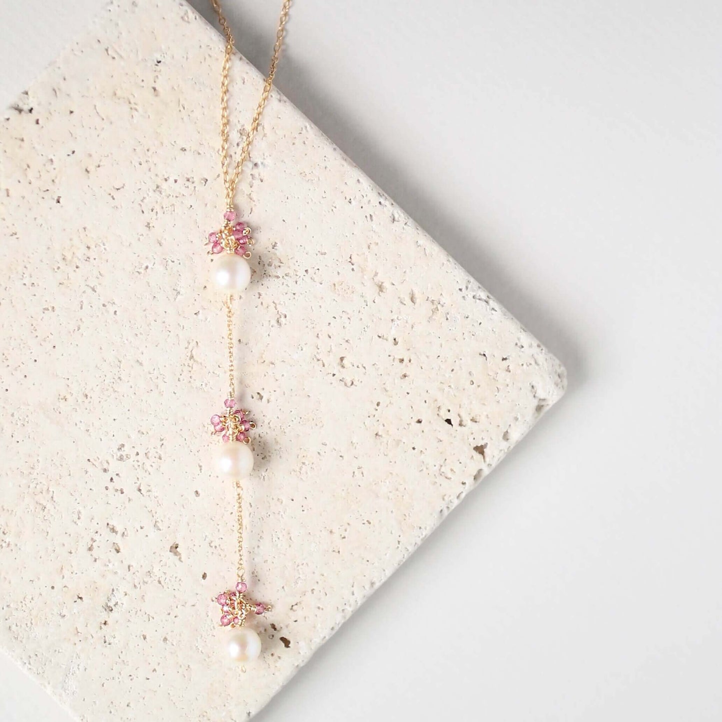 Necklace with floral and pearl details on a textured surface