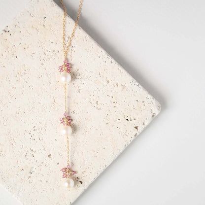 Necklace with floral and pearl details on a textured surface