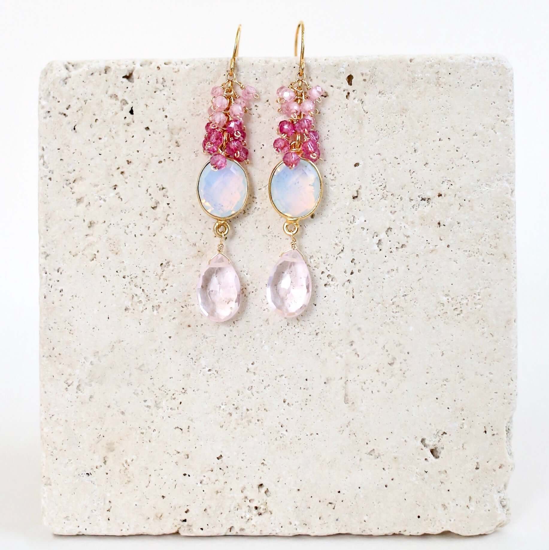 Pair of pink and gold earrings on a textured white surface