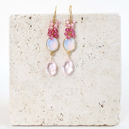 Pair of pink and gold earrings on a textured white surface