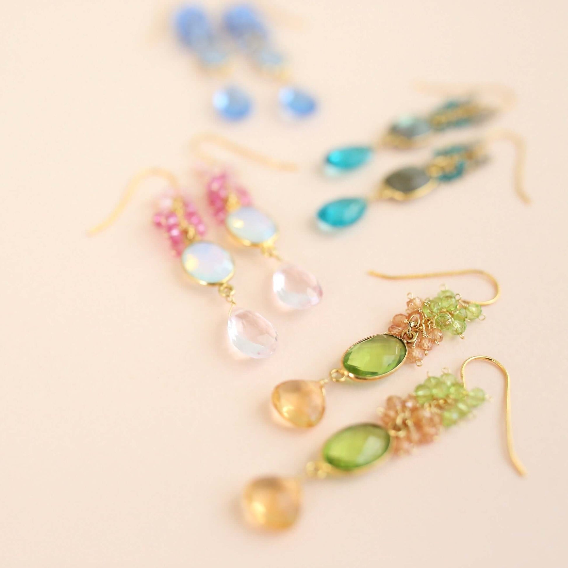Colorful earrings with gemstones on a beige background