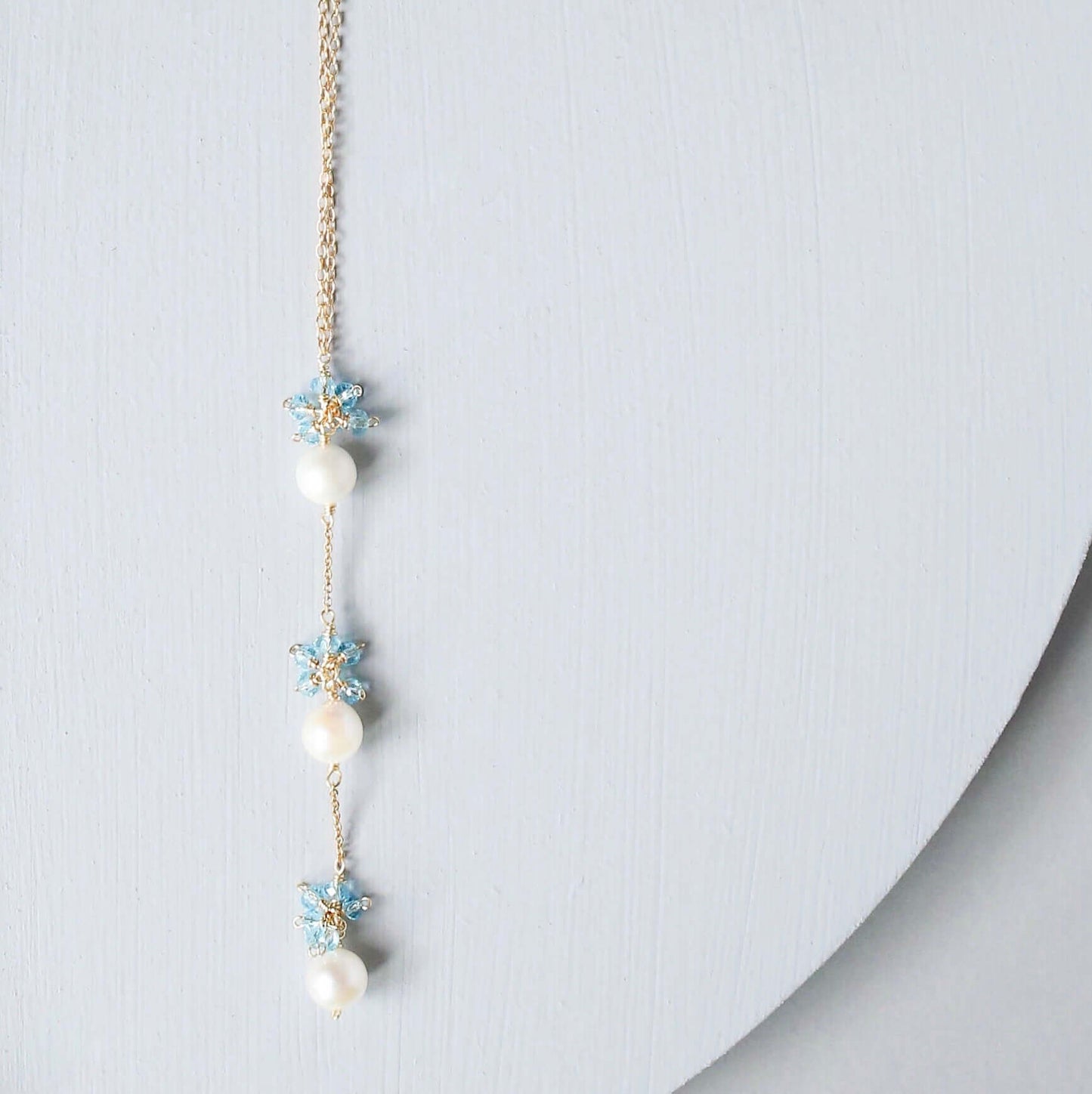 Delicate necklace with pearls and floral elements on a light gray background