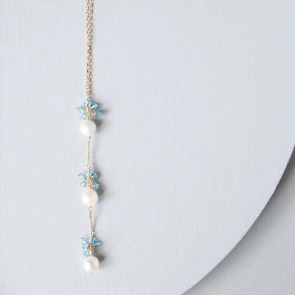 Delicate necklace with pearls and floral elements on a light gray background