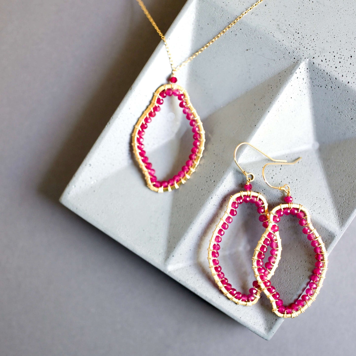 Pink beaded earrings on a gray stone surface
