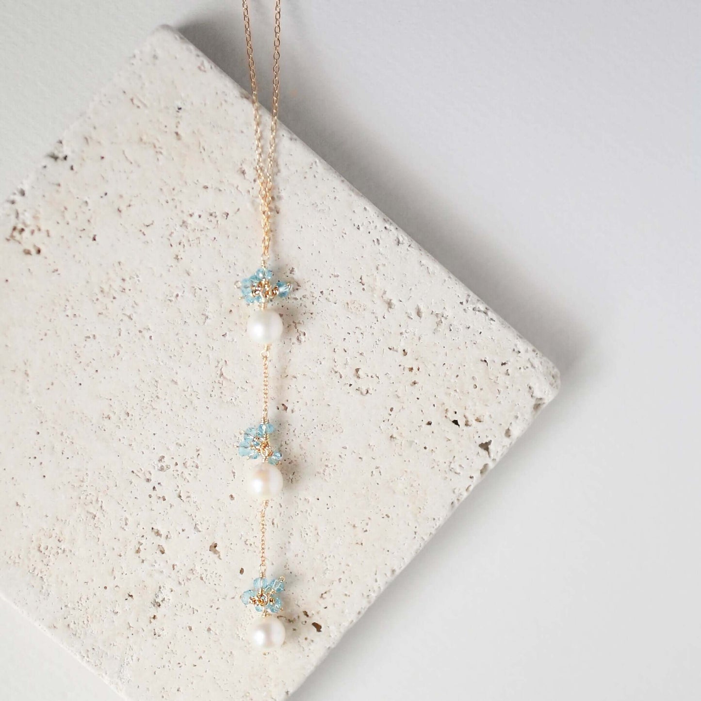 Necklace with floral and pearl details on a textured stone surface