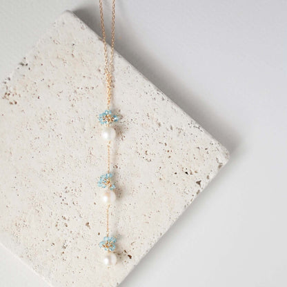 Necklace with floral and pearl details on a textured stone surface