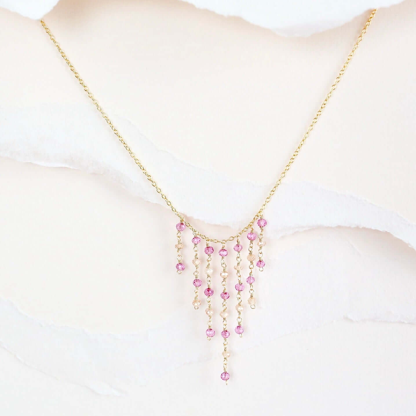 Necklace with pink beads on a mannequin bust against a white background
