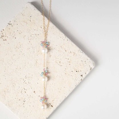 Necklace with floral and pearl details on a textured stone surface