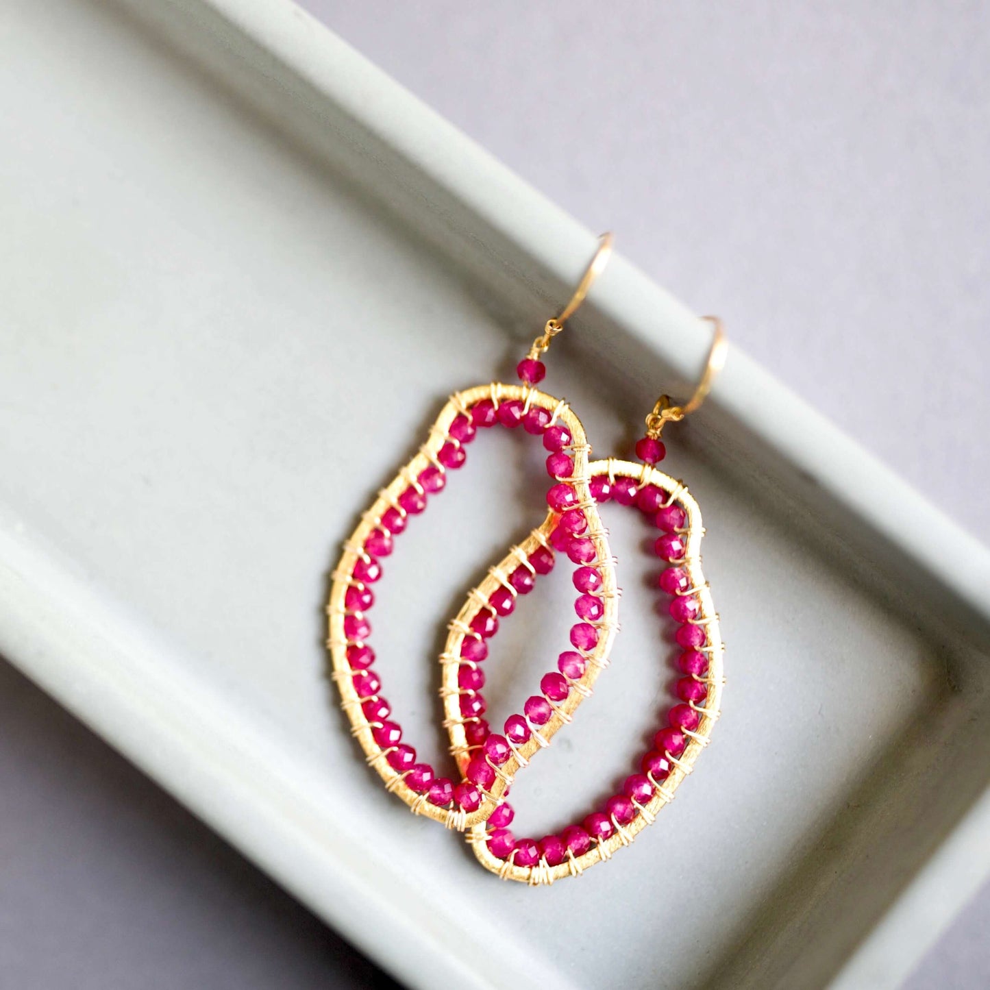 Pink beaded earrings with gold accents on a white surface