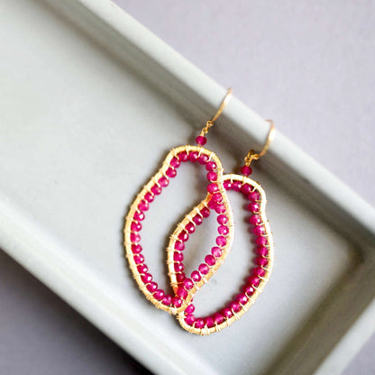 Pink beaded earrings with gold accents on a white surface