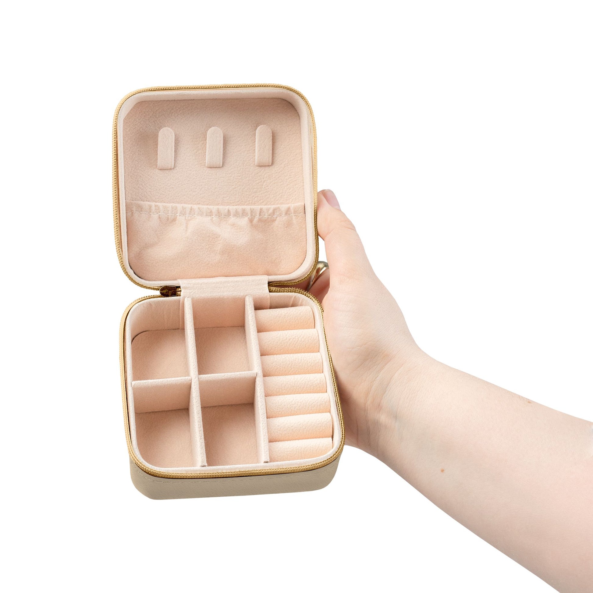 Open square tan fabric jewelry case held in a hand, featuring a peach velvet interior with compartments and ring rolls.