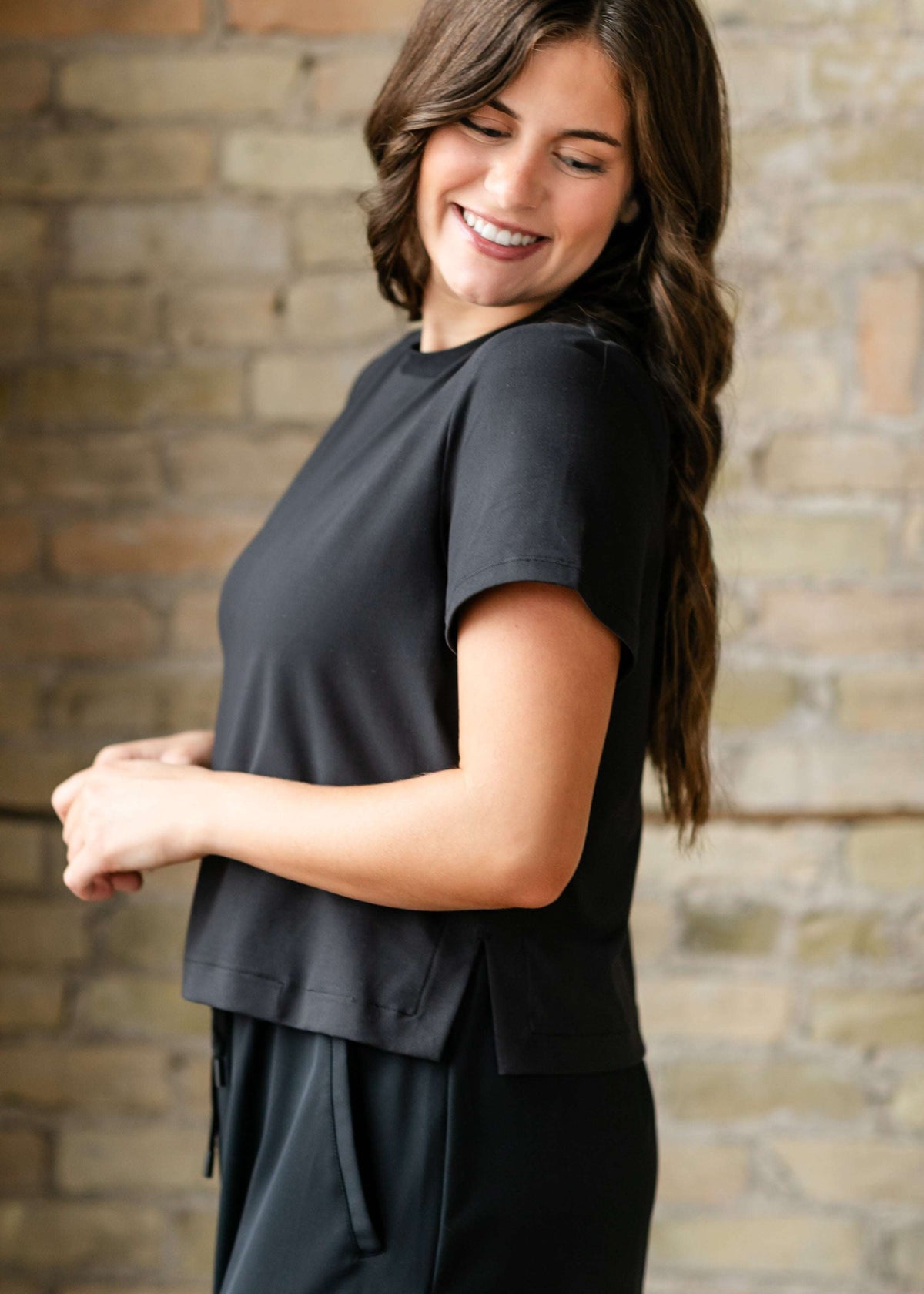 Woman wearing a black outfit against a brick wall