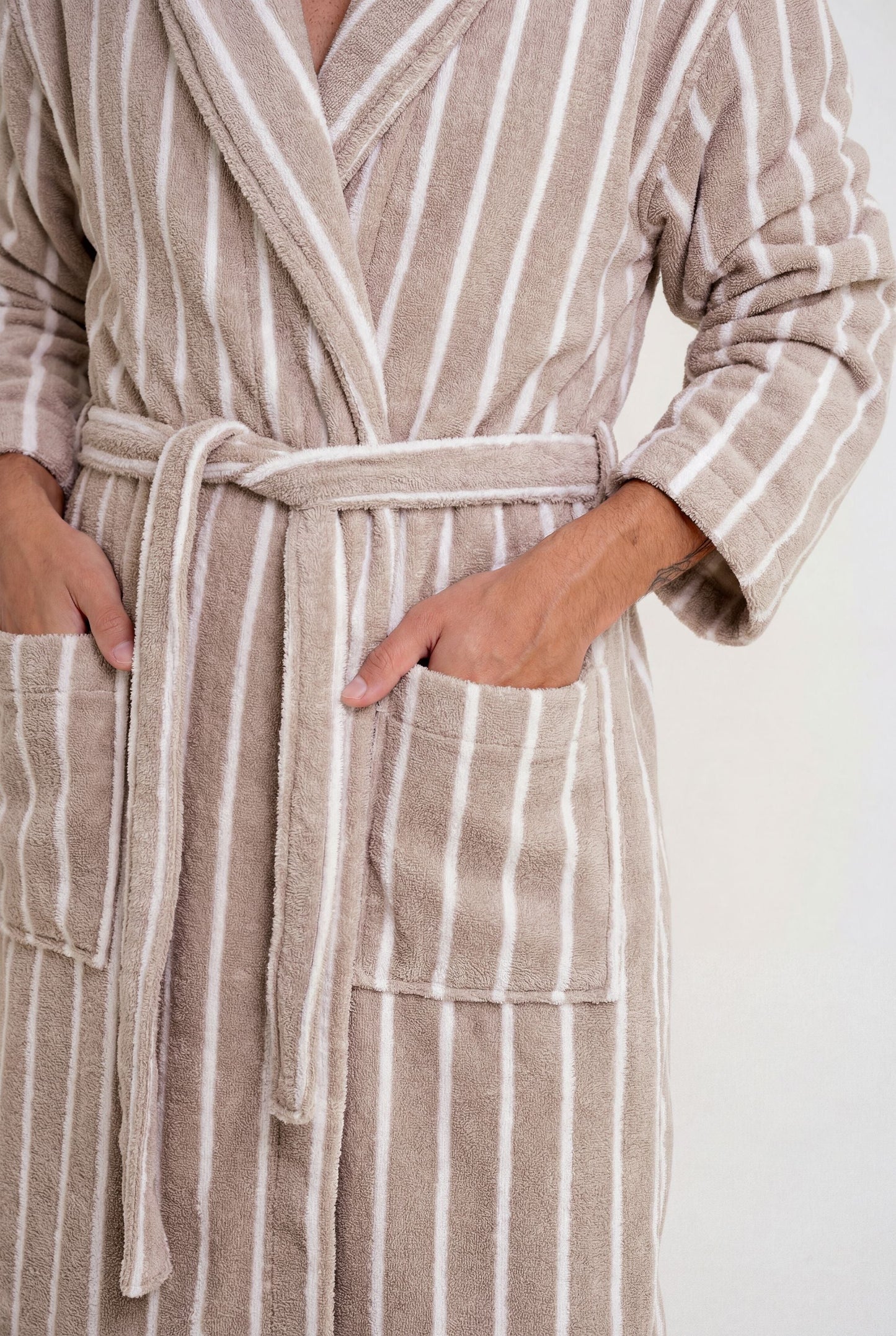 Person wearing a beige and white striped robe with a white background