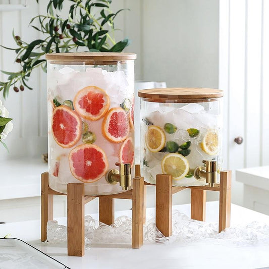 Two glass containers with fruit infusions on wooden stands in a bright room.