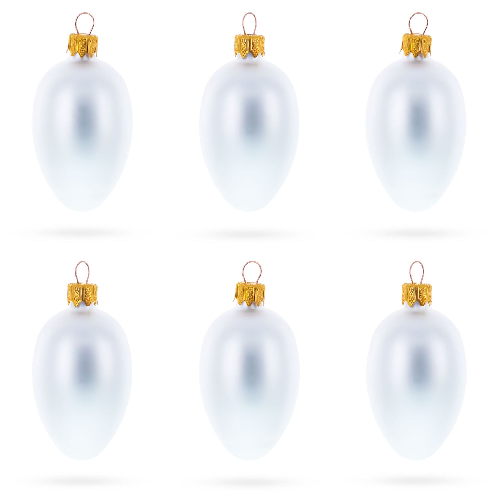 Six matte white glass egg ornaments with gold caps arranged in two rows of three on a white background.