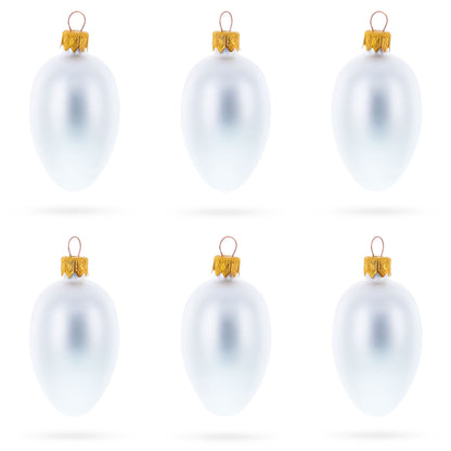 Six matte white glass egg ornaments with gold caps arranged in two rows of three on a white background.