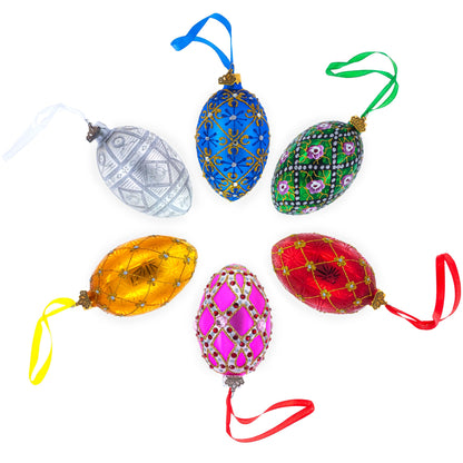 Six colorful glass egg ornaments with glitter and jewel patterns arranged in a circle on a white background.