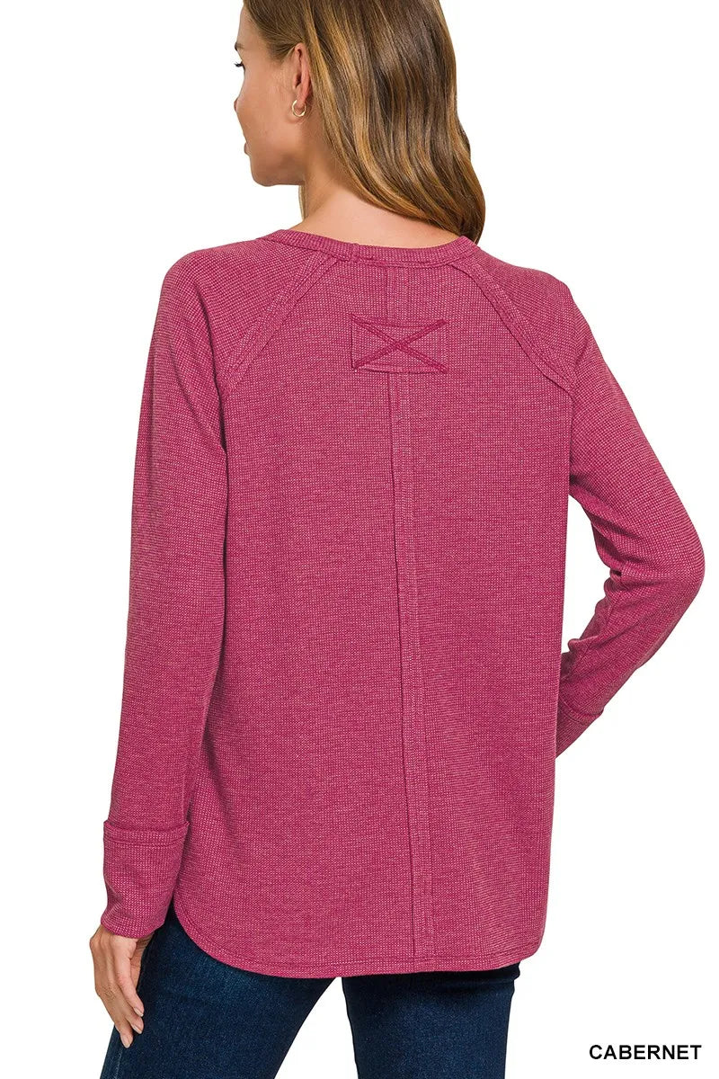 Person wearing a pink long-sleeve shirt with a logo on the back, on a white background.