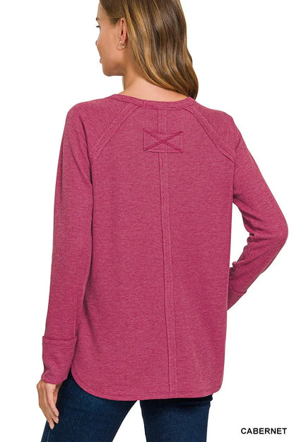 Person wearing a pink long-sleeve shirt with a logo on the back, on a white background.