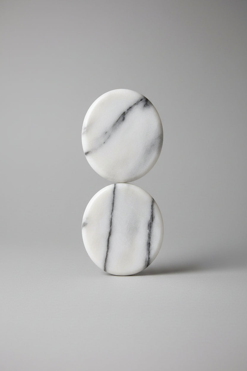 Two smooth polished oval stones with natural gray veining on a blue and green striped textured background.