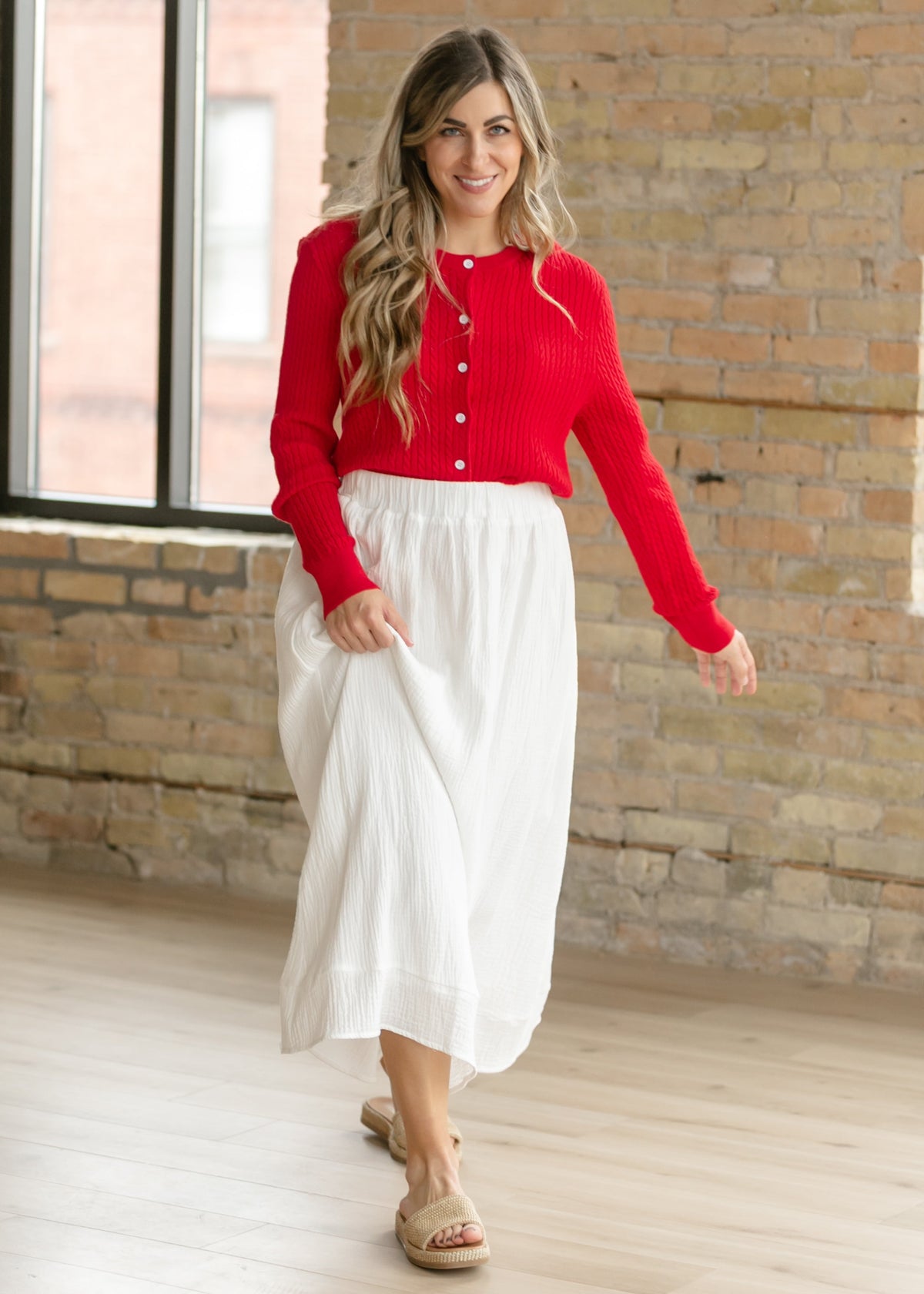 Woman wearing the Mason red cable knit button up cardigan with a flowy skirt