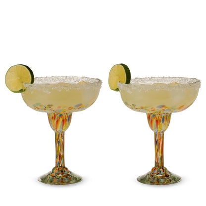 Two colorful speckled margarita glasses filled with drinks, with salted rims and lime slices.