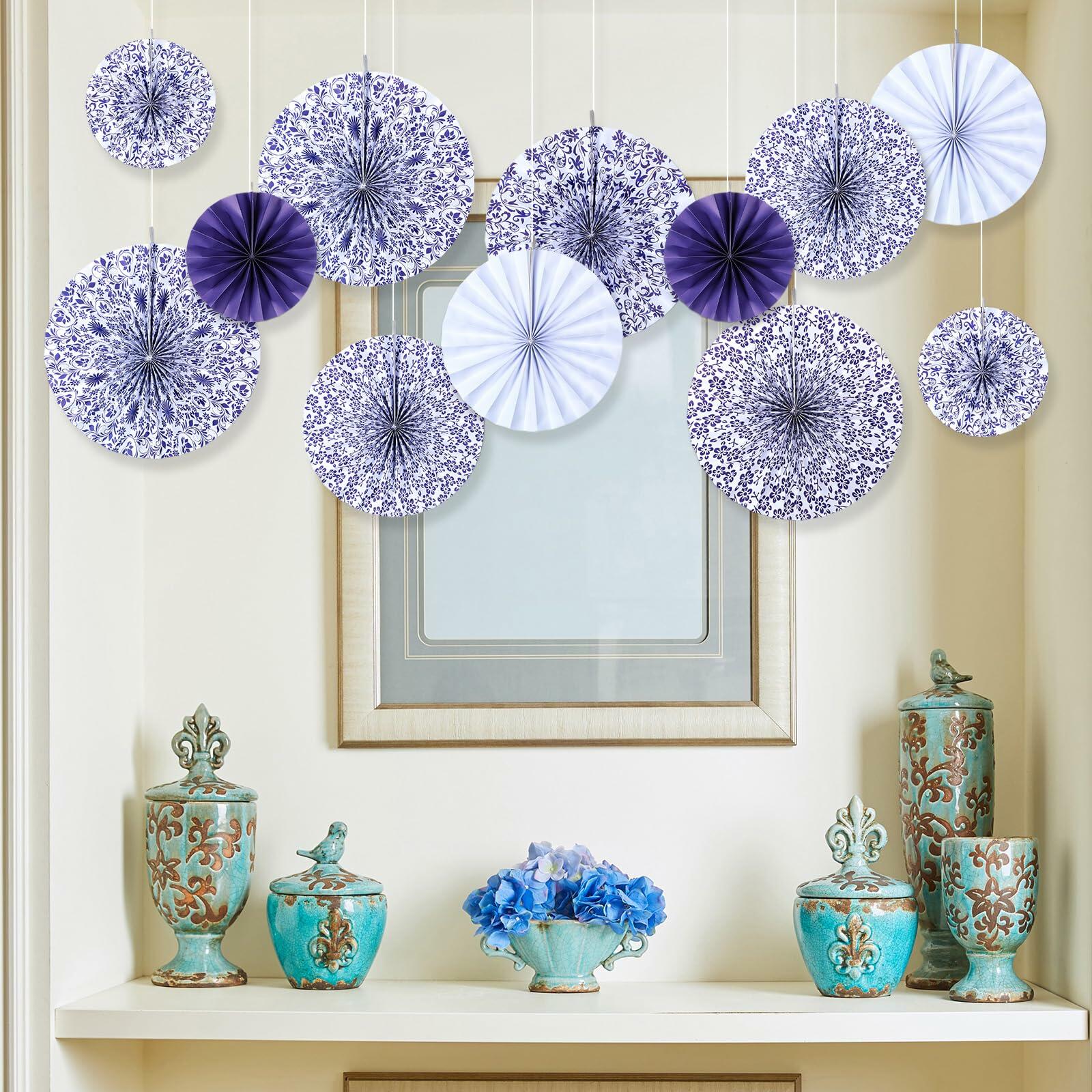 Chinoiserie hanging paper fans in blue and white, arranged decoratively above a shelf with vases and flowers.
