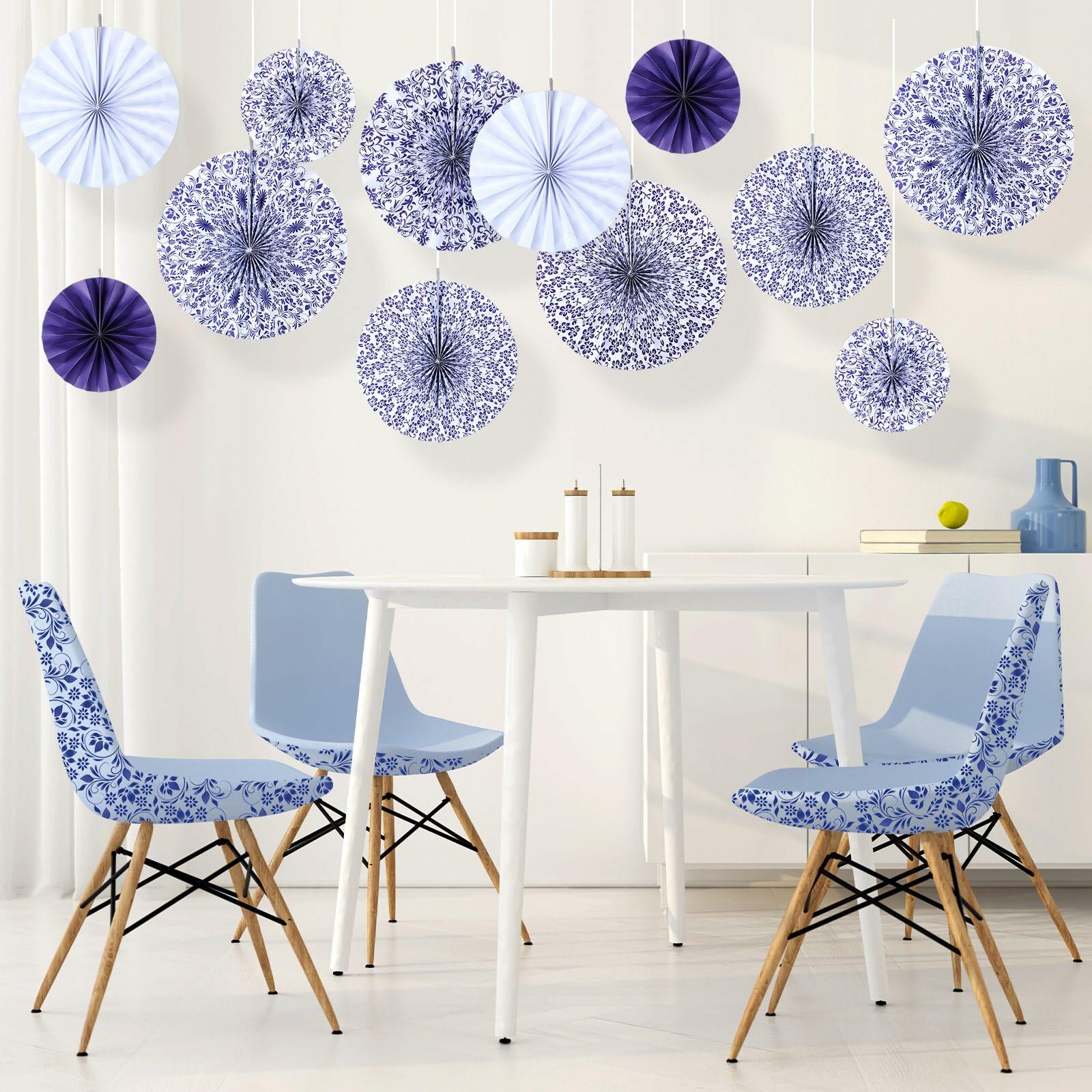 Chinoiserie hanging paper fans in blue and white, displayed above a modern dining table with blue chairs.