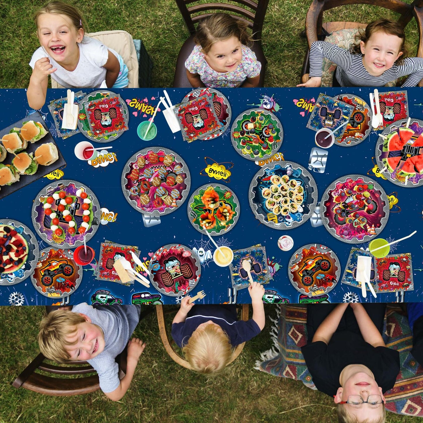 Truck-themed birthday party supplies including a tablecloth, plates, napkins, and cups arranged on a picnic table.